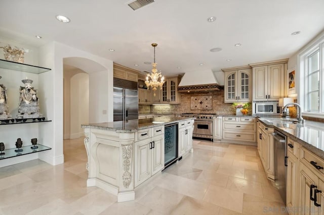 kitchen featuring pendant lighting, beverage cooler, custom exhaust hood, a center island, and built in appliances