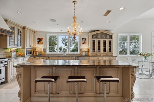 kitchen featuring a center island, hanging light fixtures, dark stone countertops, stainless steel microwave, and backsplash