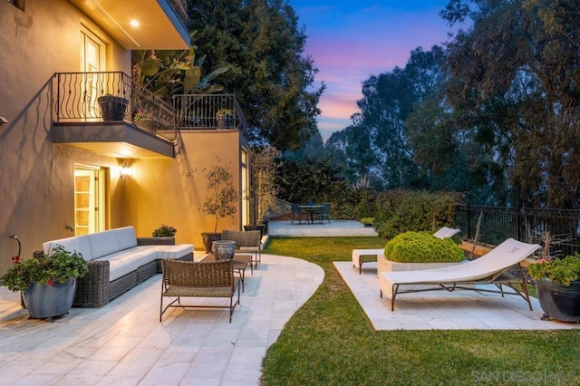 patio terrace at dusk with an outdoor hangout area and a balcony