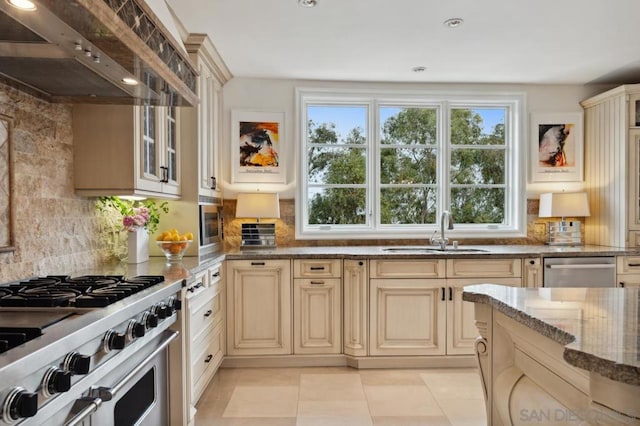 kitchen featuring premium range hood, sink, decorative backsplash, dark stone counters, and stainless steel appliances