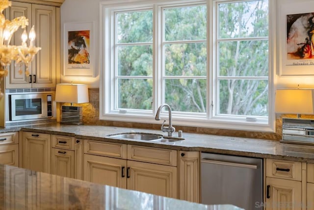 kitchen featuring light stone counters, appliances with stainless steel finishes, sink, and backsplash