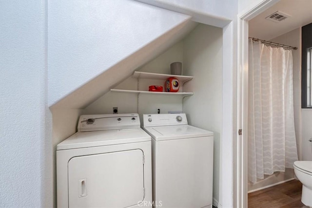 clothes washing area featuring washing machine and clothes dryer and wood-type flooring