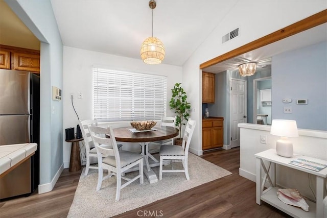 dining area featuring lofted ceiling and dark hardwood / wood-style floors