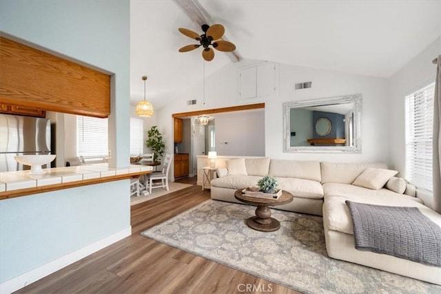 living room with dark wood-type flooring, a healthy amount of sunlight, and beamed ceiling