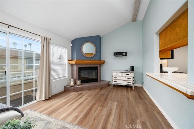 living room with hardwood / wood-style flooring, vaulted ceiling with beams, and a fireplace