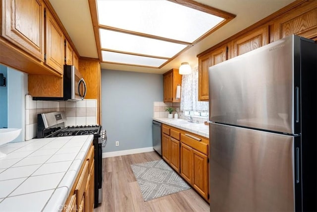 kitchen with tile counters, light hardwood / wood-style flooring, stainless steel appliances, and tasteful backsplash