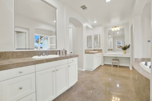 bathroom with plenty of natural light, vanity, and tiled tub