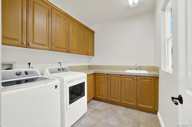 laundry room with sink, washing machine and dryer, and cabinets