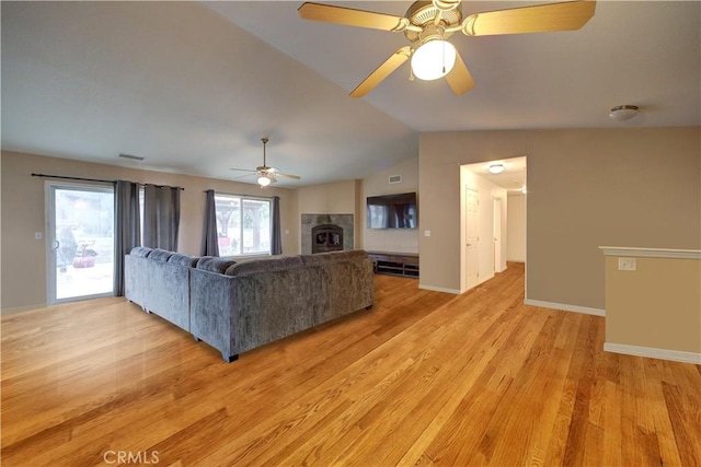 unfurnished living room featuring ceiling fan, light hardwood / wood-style flooring, a tiled fireplace, and lofted ceiling