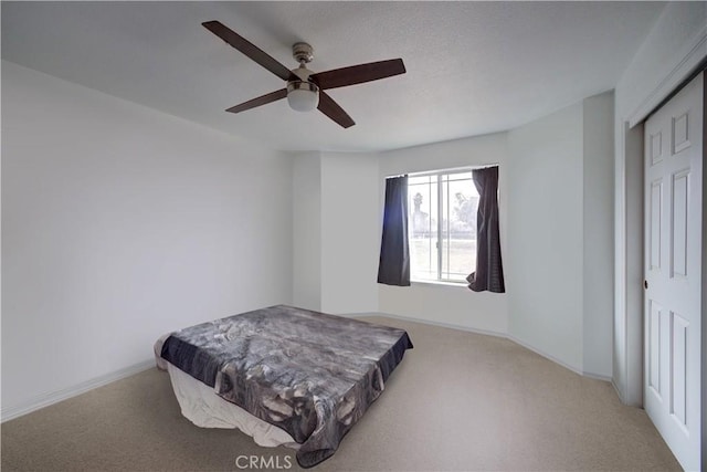 bedroom with ceiling fan, light carpet, and a closet