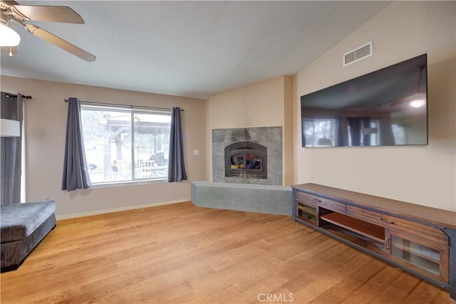 living room with a fireplace, light hardwood / wood-style flooring, and ceiling fan