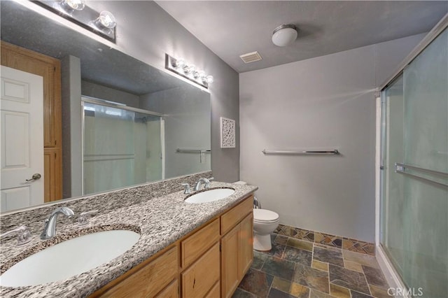 bathroom featuring vanity, a shower with shower door, and toilet