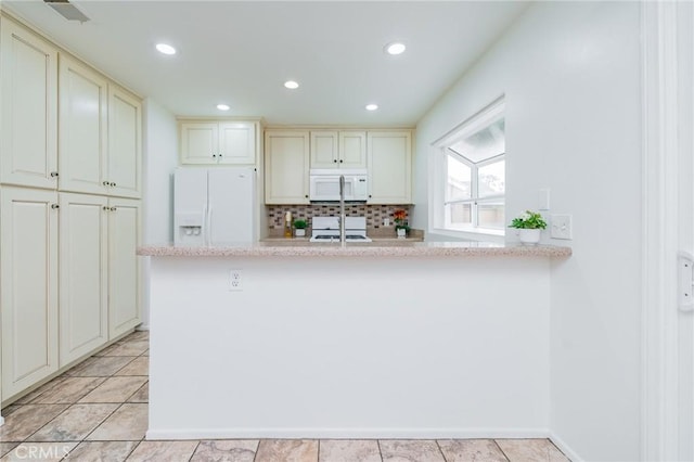 kitchen featuring light tile patterned floors, white appliances, cream cabinetry, and decorative backsplash