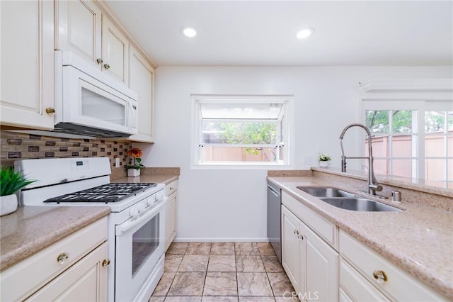 kitchen with white appliances, a healthy amount of sunlight, sink, and decorative backsplash