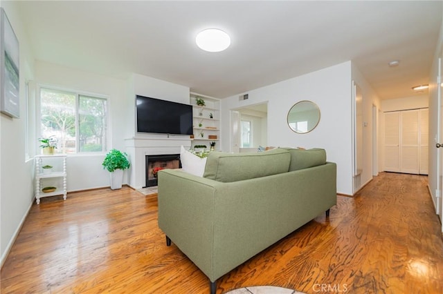 living room with light wood-type flooring and built in shelves