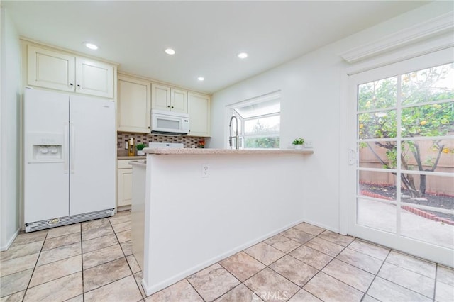 kitchen with white appliances, kitchen peninsula, decorative backsplash, and light tile patterned floors