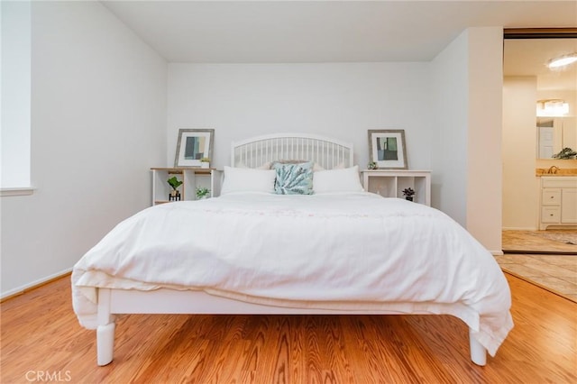 bedroom featuring hardwood / wood-style flooring, sink, and ensuite bath