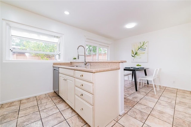 kitchen featuring dishwasher, white cabinetry, sink, and light tile patterned floors