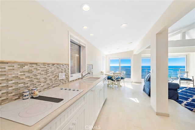 kitchen with lofted ceiling, sink, a water view, white cabinetry, and white appliances