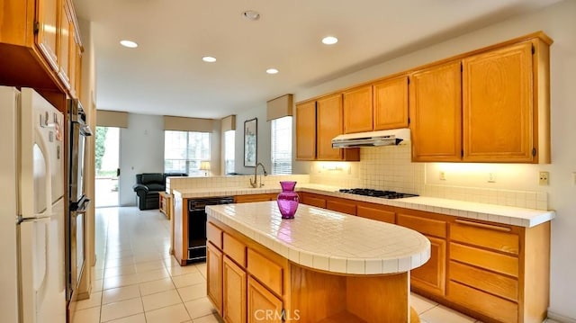 kitchen with a kitchen island, tile countertops, dishwasher, white fridge, and kitchen peninsula