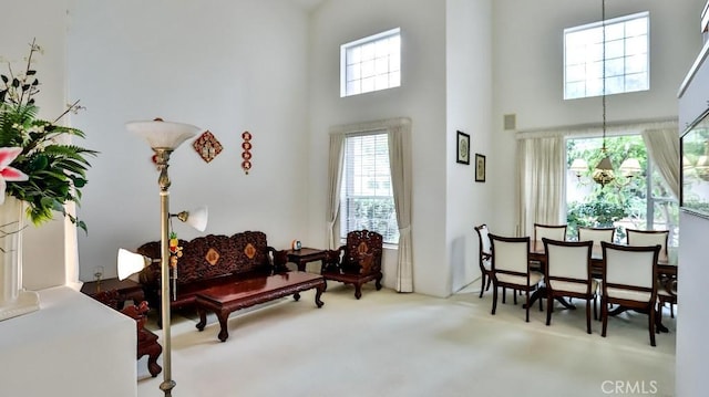 living area with a notable chandelier, a towering ceiling, and carpet