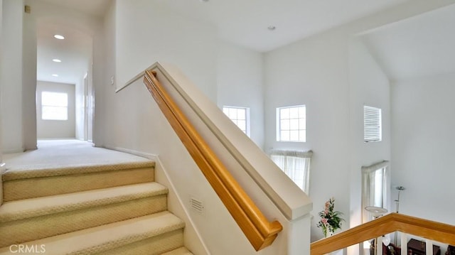 stairs featuring a towering ceiling and carpet floors