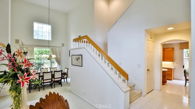 stairs with a towering ceiling and a chandelier