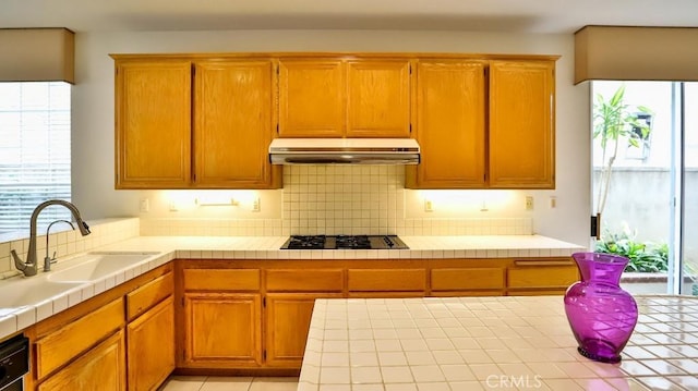 kitchen featuring sink, tile countertops, decorative backsplash, and black appliances