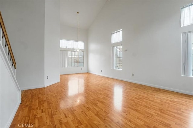 unfurnished living room featuring a high ceiling and light wood-type flooring