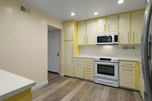 kitchen with appliances with stainless steel finishes, decorative backsplash, and light wood-type flooring