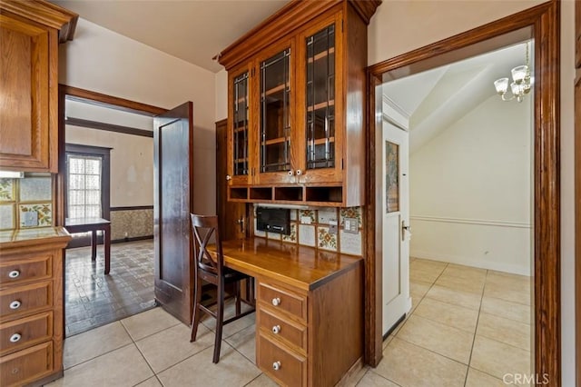 tiled home office featuring built in desk and a chandelier