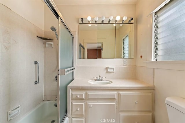 full bathroom with vanity, toilet, and combined bath / shower with glass door