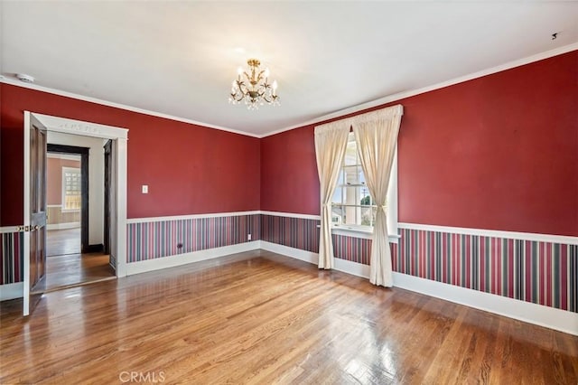 unfurnished room featuring crown molding, wood-type flooring, and a chandelier