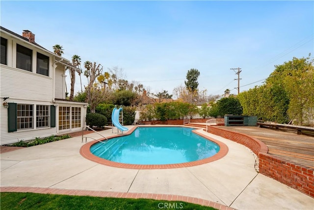 view of pool featuring a wooden deck, a patio, and a water slide