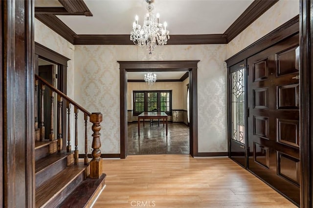 foyer entrance featuring ornamental molding, a chandelier, and light hardwood / wood-style floors