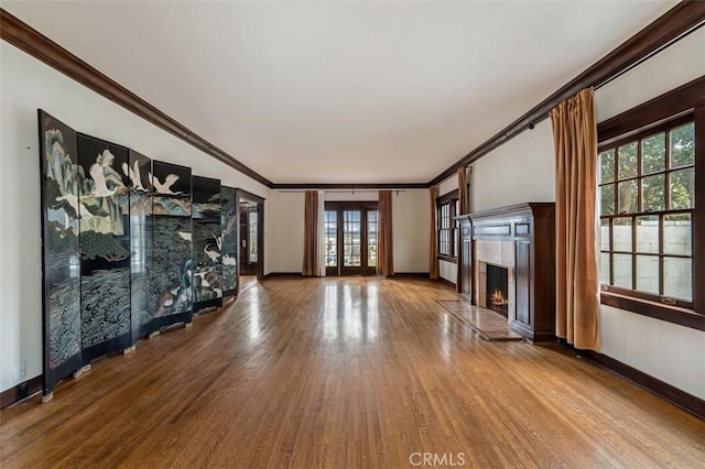 unfurnished living room featuring crown molding, hardwood / wood-style flooring, a high end fireplace, and french doors