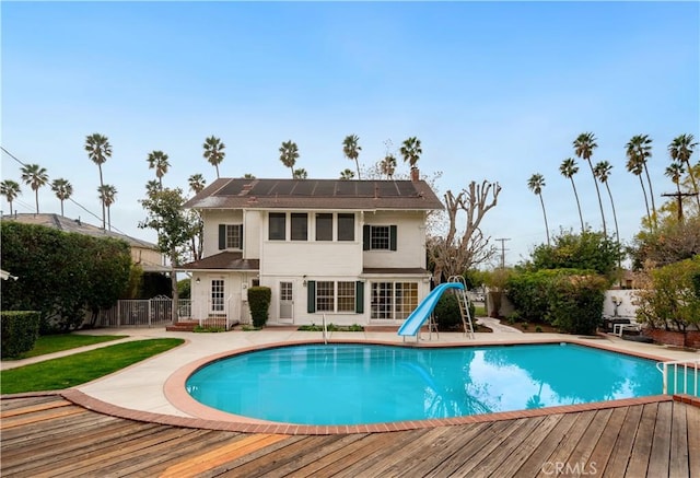 view of pool with a water slide and a deck