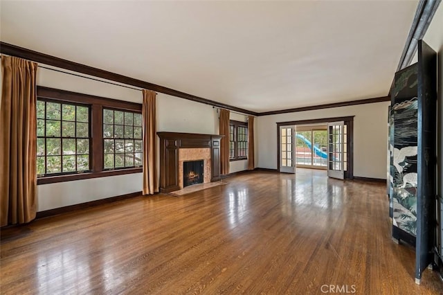 unfurnished living room with hardwood / wood-style flooring, a high end fireplace, ornamental molding, and french doors