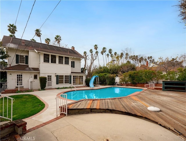 view of pool featuring a patio, a water slide, and a deck