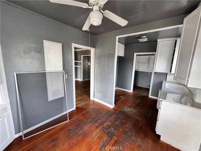 interior space featuring dark wood-type flooring, a ceiling fan, and baseboards