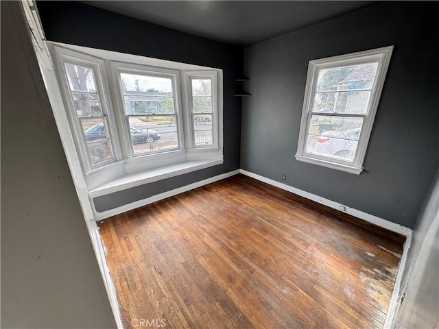 empty room with baseboards and wood-type flooring