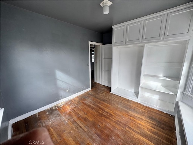 unfurnished bedroom with baseboards, wood-type flooring, and a closet