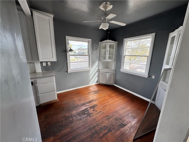 unfurnished dining area featuring a wealth of natural light, dark wood-type flooring, and ceiling fan