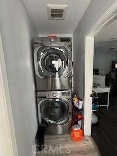 laundry area featuring stacked washer and dryer and hardwood / wood-style flooring