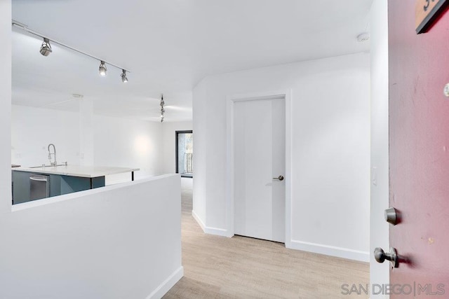 hallway featuring rail lighting, light hardwood / wood-style floors, and sink