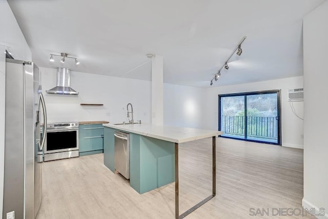 kitchen with wall chimney exhaust hood, sink, a breakfast bar area, a center island with sink, and stainless steel appliances