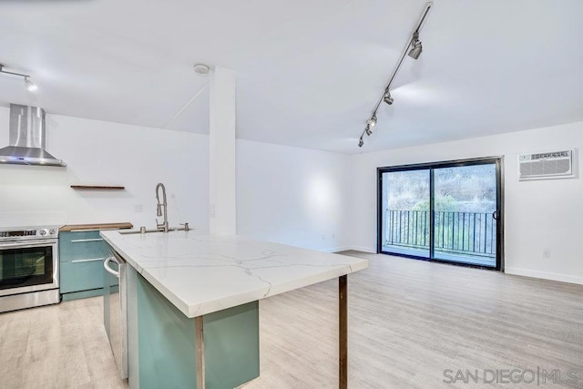 kitchen featuring green cabinetry, a kitchen island with sink, wall chimney exhaust hood, and stainless steel electric range