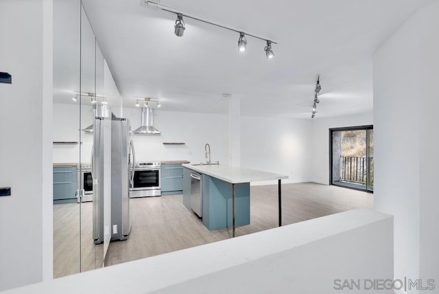 kitchen with pendant lighting, wall chimney range hood, a breakfast bar, stainless steel appliances, and a center island