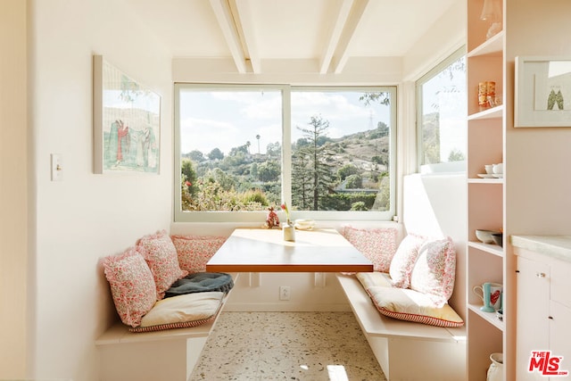 sunroom featuring breakfast area, plenty of natural light, and beamed ceiling