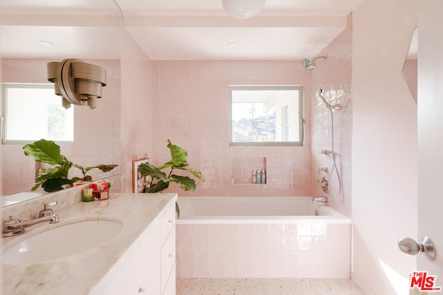 bathroom featuring tiled shower / bath combo, vanity, and tile walls